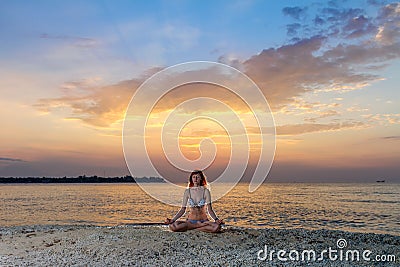 Woman in yoga lotus meditation at sunset