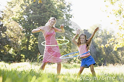 Woman and young girl outdoors using hula hoops