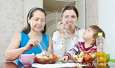 Women with baby girl eats vegetables salad