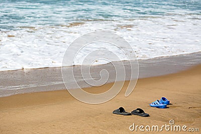Women s and Men s Slippers on a Sandy Ocean Beach