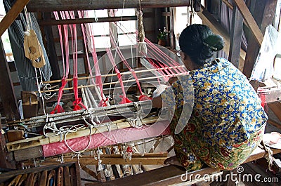 Women weaving red silk into a scarf