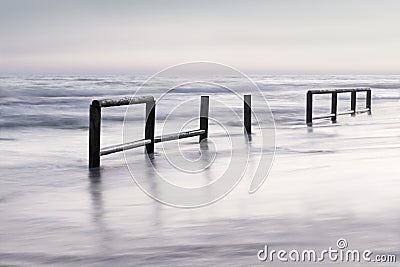 Wooden fence in sea water at sunset