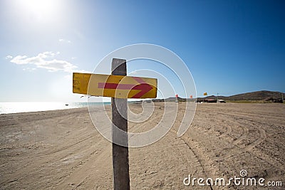 Wooden sign with an arrow and the beach in the backgound