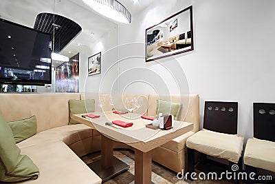 Wooden table, beige leather sofa in cozy restaurant