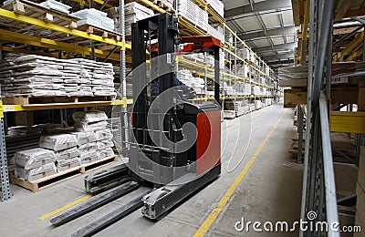 Worker with forklift in wood warehouse