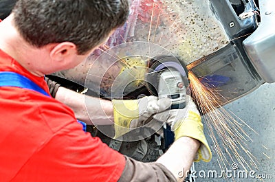 Worker grinding car panel