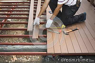 Worker installing wood floor for patio