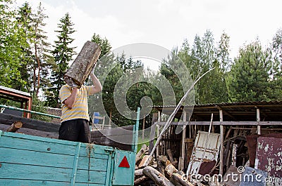 Worker man unload tree logs firewood from trailer