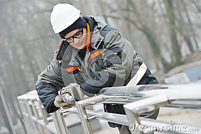 Worker polishing metal fence barrier