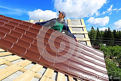 Worker puts the metal tiles on the roof