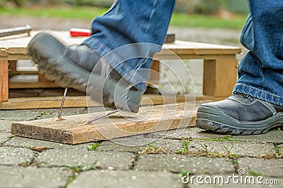 Worker with safety boots steps on a rusty nail