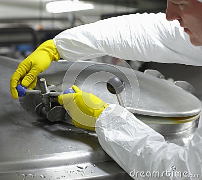 Worker in yellow gloves closing industrial process tank