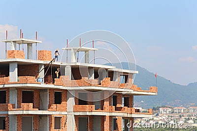 Workers erect balconies from brick in new building
