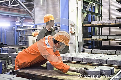 Workers at the machine on stone blocks drying