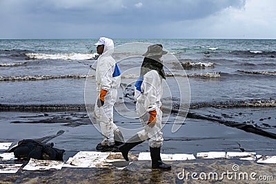 Workers remove crude oil from a beach