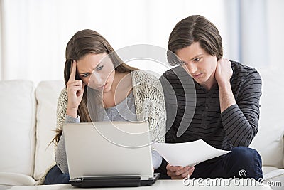 Worried Couple Calculating Finance On Laptop
