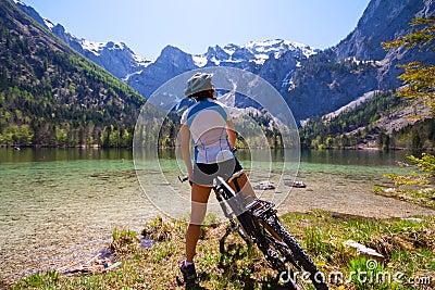 Yaung woman riding a bike beside Alpine lake