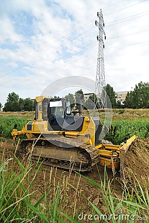 Yellow bulldozer creating route on riverbed