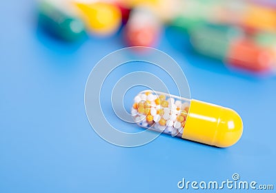 Yellow capsule with medication on blue background