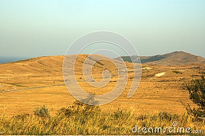 Yellow dry grass field, blue sea and sky.