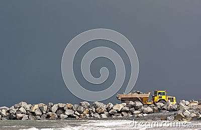 Yellow dumper truck building coastal defence works