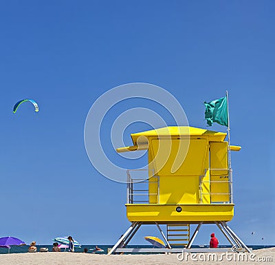 Yellow Life Guard Tower at the beach with people, kite surfer and blue sky