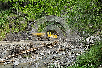 Yellow mining dump truck on forest road