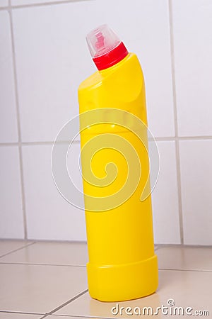 Yellow plastic bottle of cleaning product on tiled floor