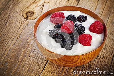Yogurt with forest berries in wooden bowl
