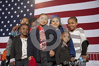 Young African American children stand in front of American Flag
