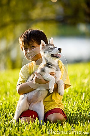 Young Asian boy hugging puppy sitting on grass