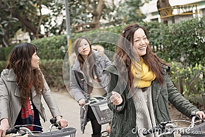 Young Asian woman riding bicycle with friends