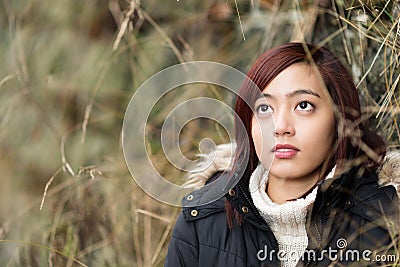 Young Asian woman standing daydreaming