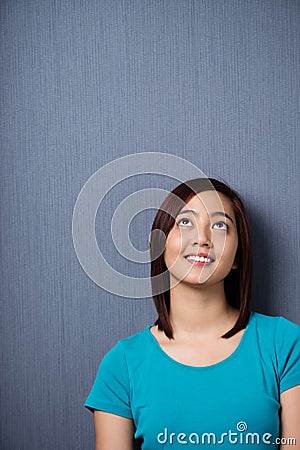 Young Asian woman standing daydreaming