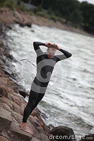 Young athlete on rocky beach prepearing to swim