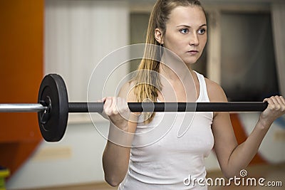 Young athlete woman exercising with barbell