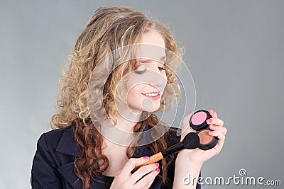 Young attractive make up artist with brush over grey