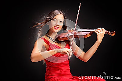 Young attractive woman in red dress playing the violin