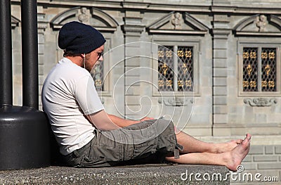 Young barefoot man listen music