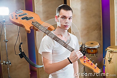 Young bass player with tattoo standing with guitar