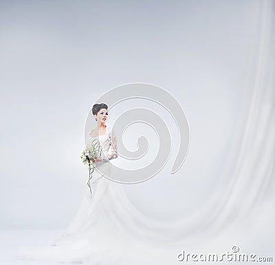 Young and beautiful bride standing with a flower bouquet