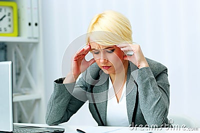 Young beautiful businesswoman thinking at her workplace