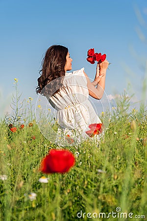 Young beautiful calm girl dreaming on a poppy field, summer outdoor.