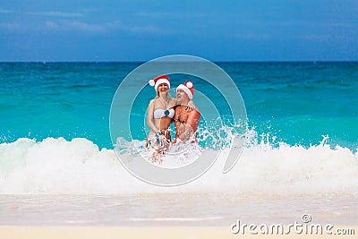 Young beautiful couple in love having fun in the waves dressed i