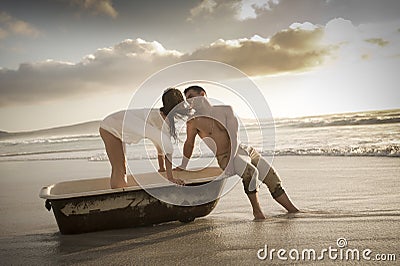 Young beautiful couple spending afternoon on beach with old bath tub