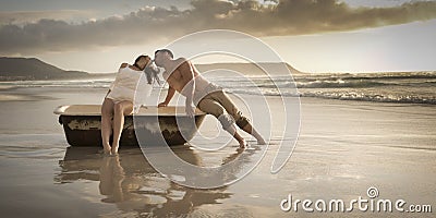 Young beautiful couple spending afternoon on beach with old bath tub