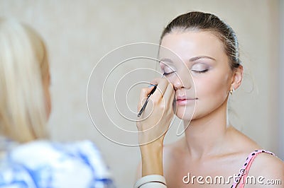 Young beautiful girl applying make-up by make-up artist