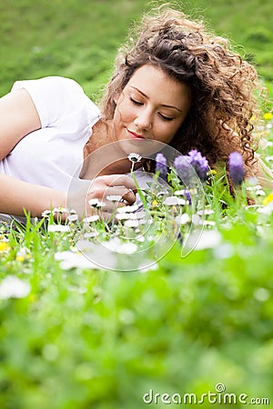 Young beautiful girl laying on the flowers field, summer concept
