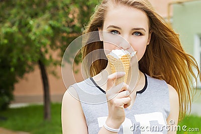 Young beautiful happy girl with long hair in a Sunny day walking around the city and eat ice cream
