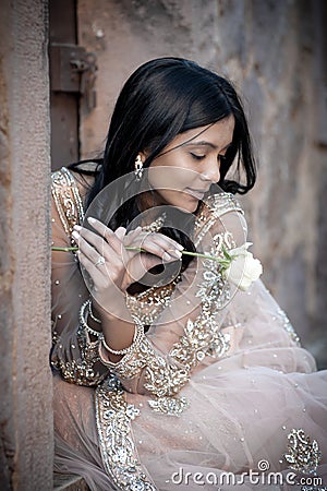 Young beautiful Indian Woman sitting against stone wall outdoors